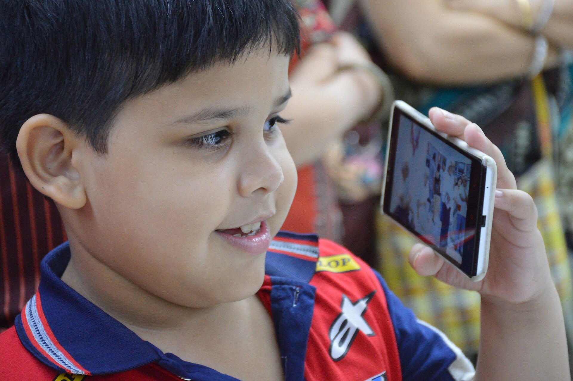 A young boy smiling at a smartphone