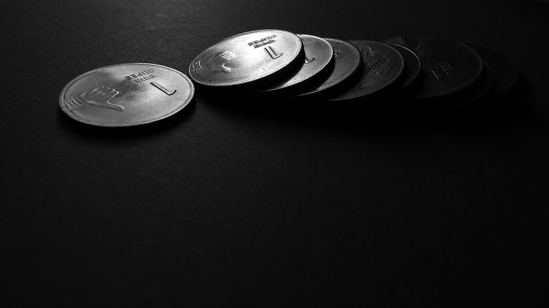 Indian one rupee coins on a dark surface